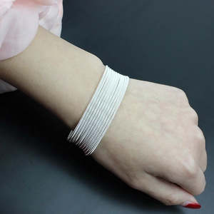 Close-up of stacked silver spring wire guitar string bracelets on woman's wrist