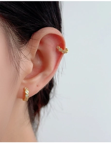 Close-up of a gold C-shaped ear cuff with micro-pave crystals on a person's ear