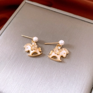 Gros plan de boucles d'oreilles cheval à bascule plaqué or 14k avec oxydes et perles