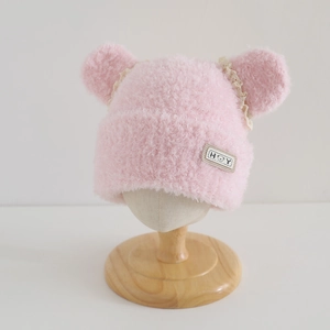 Detail of pink plush girls' hat featuring cute ears, lace trim and bear patch logo