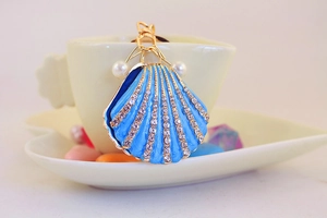 Detailed view of blue seashell keychain with golden plating and sparkling rhinestones