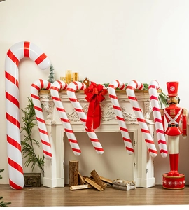 Inflatable red and white Christmas candy cane decorations arranged by a cozy fireplace