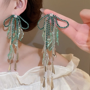 Detail of forest style bow earrings with green crystals and long silver tassels