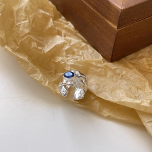 Macro detail of irregular silver hammer texture ring with oval blue gemstone