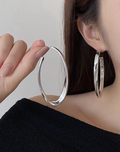 Macro view of silver large twisted hoop earrings on model showing metal texture and size
