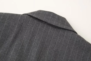 Détail de la texture du tissu gris foncé à rayures et couture sur le revers du gilet