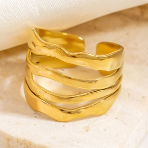 Macro shot of gold-plated four-layer wave open ring on elegant white stone and silk