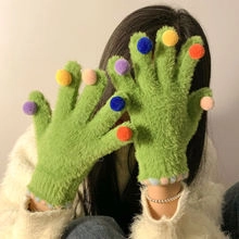 Detailed view of green plush gloves featuring colorful pom-poms on each fingertip