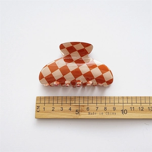 Detail view of the 8.5cm orange checkerboard claw clip with a size measurement ruler