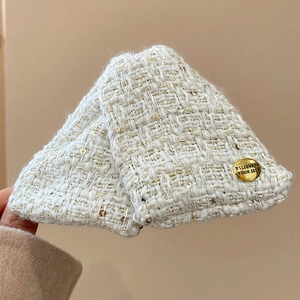 Close-up of cream white tweed hair claw clip with golden sequins and metal button detail