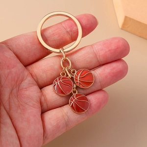 Detailed close-up of three orange basketball pendants with gold lines on a keychain