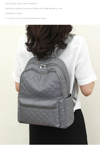 Vista trasera de mochila gris acolchada con múltiples bolsillos en la modelo