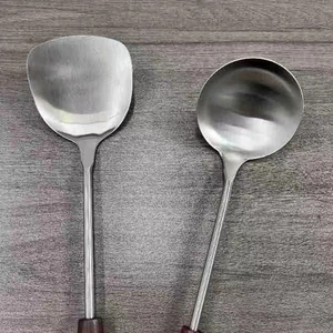 Detail of stainless steel spatula and soup ladle set with vintage dark wooden handles
