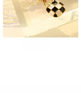 Detail of a retro gold square pendant with black and white checkerboard enamel pattern