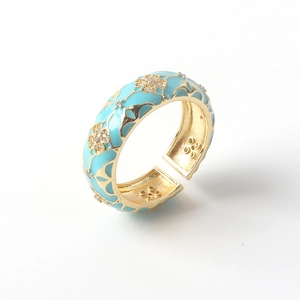 Detail of 18K gold ring featuring blue enamel clover and sparkling zircon inlays