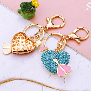 Macro detail of heart-shaped keychains with red and blue rhinestones on a marble surface