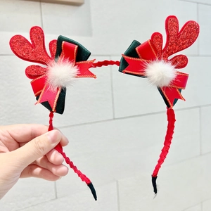 Detail of Christmas headband with red glitter antlers, satin bow and white plush balls