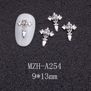 Macro shot of silver alloy cross nail art charm with wings and center rhinestone