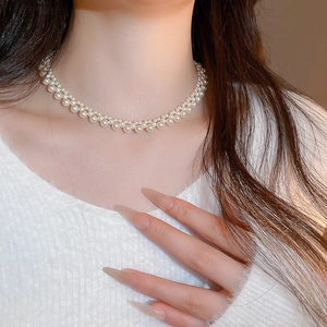 Close-up of elegant double-row pearl choker necklace on model with white sweater