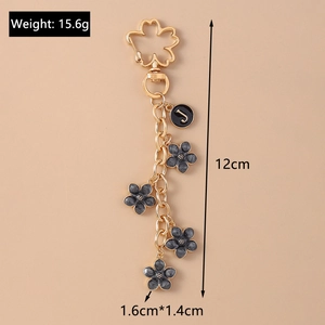 Detail showing gold cherry blossom clasp, black enamel flower, and J initial charm pendant
