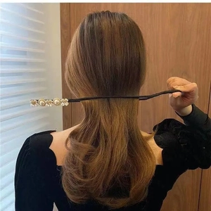 Detalle de accesorio para moños con flores de perlas blancas sobre tela oscura fina