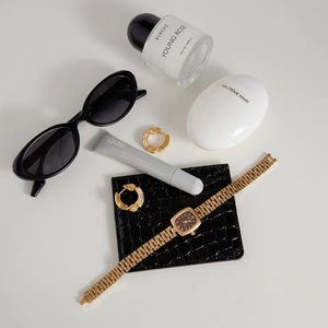 Close-up of gold hoop earrings with sparkling crystals and a luxury metal watch