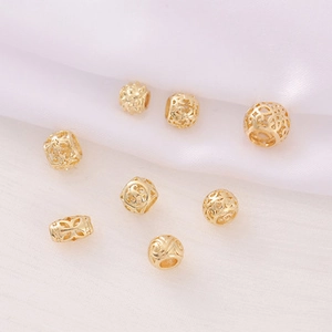 Detailed view of hollow gold-plated beads with intricate engraved patterns on silk