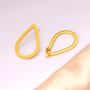 Detailed view of golden teardrop hollow earrings with butterfly backings and satin fabric