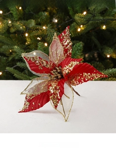 Detail of red velvet Christmas flower with gold sequins on a lighted tree