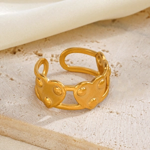 Bague cœur dorée ajustable en acier inoxydable sur une surface en pierre texturée