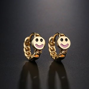 18K gold plated hoop earrings with pink and black smiley face charms on black surface