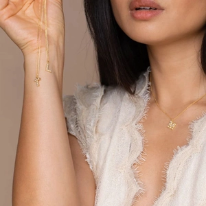 Close-up of gold-plated letter pendants with micro-pave crystals on a model neck