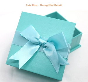 Detail of square blue jewelry gift box with a silk bow and textured surface finish