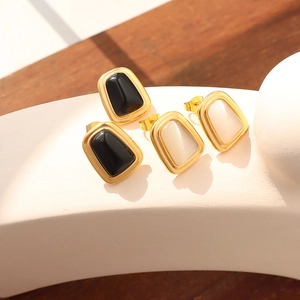 Elegant gold earrings set featuring black and white cat eye stones on a white curved surface