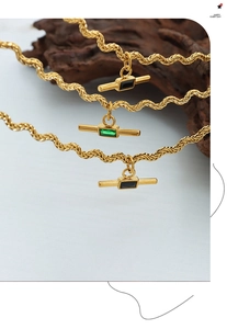 Macro shot of wavy gold chain necklaces with black and green rectangular stone pendants