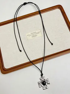 Detailed view of vintage silver cross pendant with black heart on adjustable cord