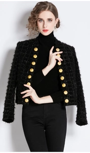 Close-up of golden lion head buttons and textured black tweed fabric on a fitted jacket