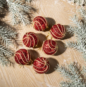 Detail view of 6 red Christmas balls with gold sequins and spiral beads on a wooden surface