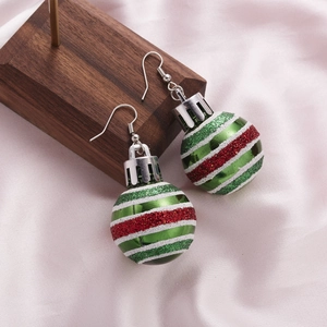 Detail of green and red striped Christmas ball earrings on walnut wood stand