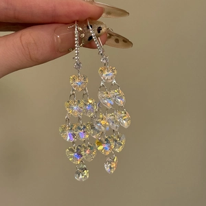 Détail des boucles d'oreilles à pompon coeur en cristal de zircon avec reflets irisés