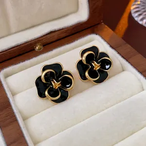 Detail of vintage camellia flower stud earrings with black enamel and gold metallic edges