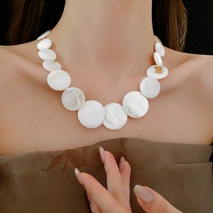 Bohemian geometric shell necklace with graduated white discs on a model for a beach look