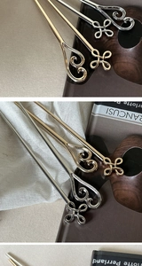 Detailed view of four metal hairpins in gold and silver with hollow heart motifs