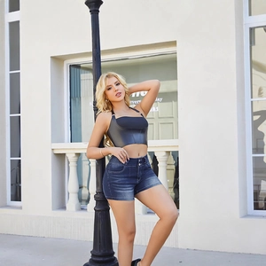 Conjunto de pantalones cortos vaqueros sexys y top corto de cuero negro en un entorno exterior