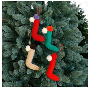 Dettaglio degli ornamenti delle calze di Natale in maglia appese a un albero di Natale verde
