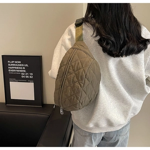 Close-up of military green quilted nylon crossbody bag with wide strap on a model