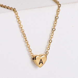 Close-up of a 18k gold plated heart pendant necklace with black engraved letter A detail