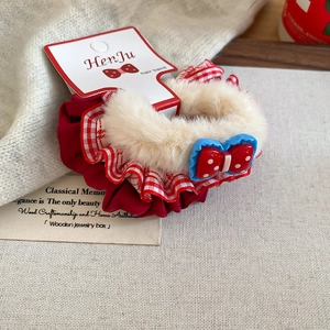 Detail of red satin hair scrunchie with faux fur trim and polka dot bow accessory