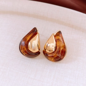 Detail of tear-drop resin earrings in amber and 18K gold plated metal finish