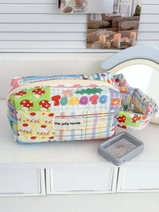 Close-up of rainbow quilted fabric storage bag with cartoon mushroom and cake patterns